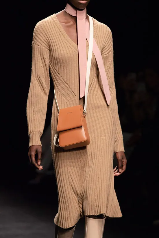 Модель в вязаном бежевом платье миди, высокие сапоги и сумочка
