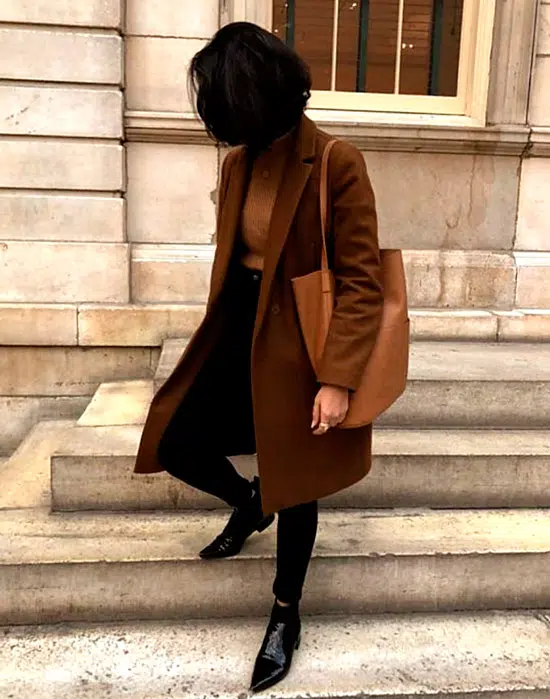Девушка в черных джинсах, коричневое пальто и лакированные ботинки с острым носом