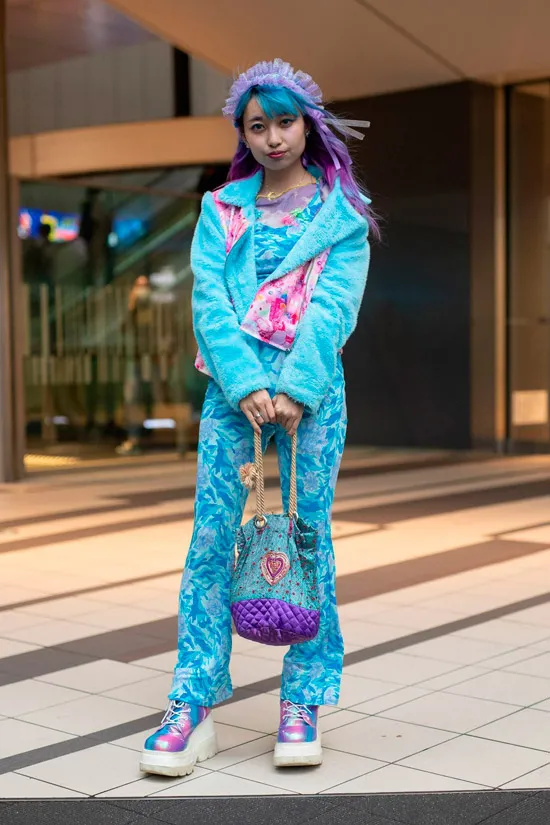 Девушка в голубых брюках, куртке и фиолетовые кроссовки на платформе