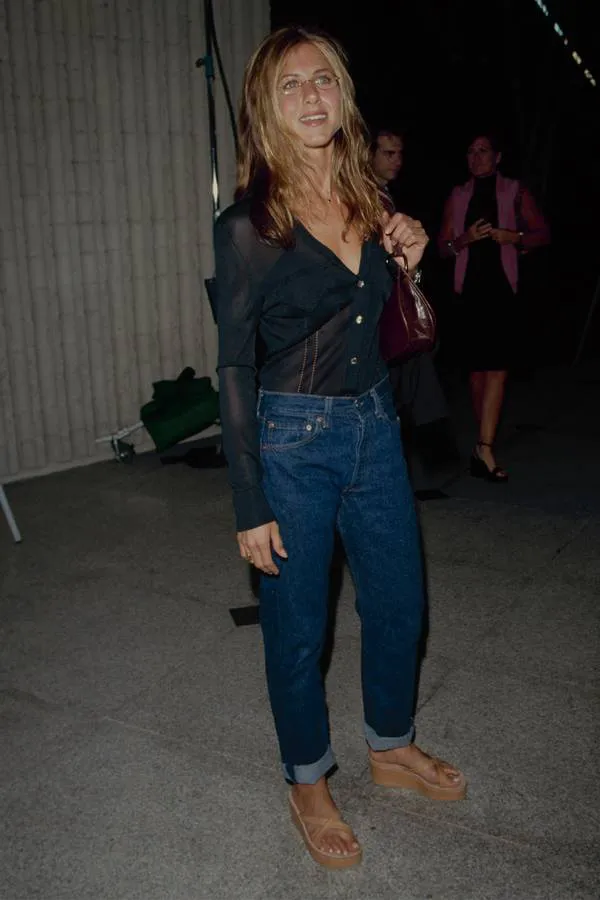 Дженнифер Энистон в черной блузке, синии джинсы с высокой талией и сандалии