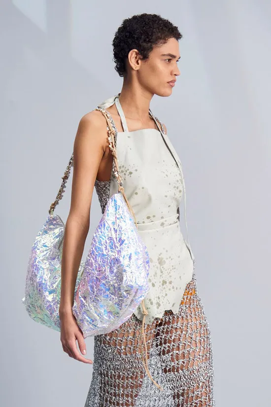 Модель Acne Studios в необычном платье с сеткой и с большой серебристой сумкой