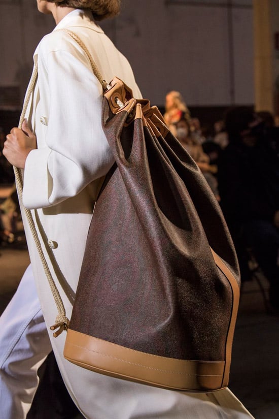 Модель Etro в белом длинном плаще и с коричневой сумкой мешок