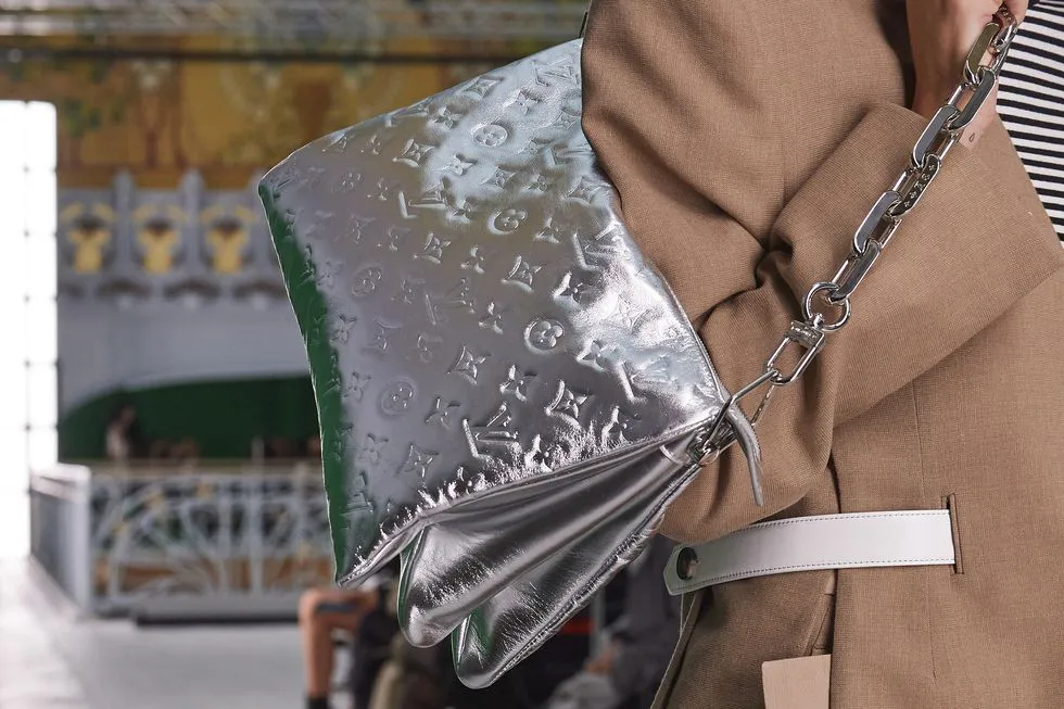 Модель Louis Vuitton в бежевом пиджаке и с серебристой сумкой на цепочке