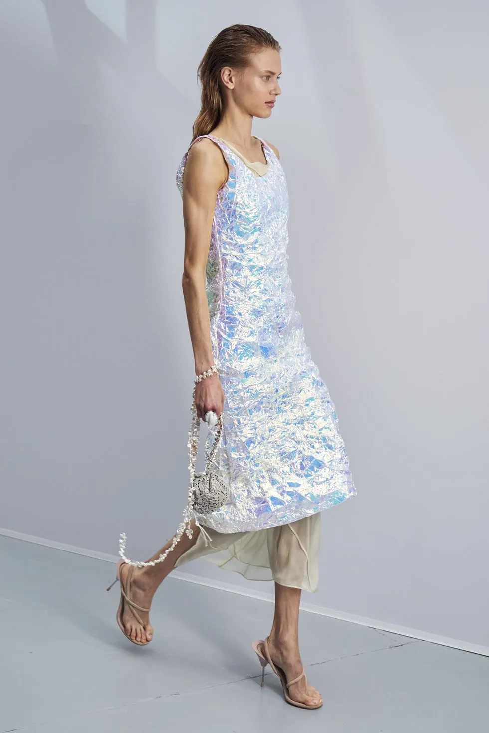 Модель в серебристом блестящем платье миди и бежевых босоножках на ремешках от Аcne