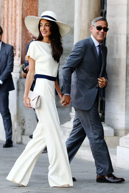 Амаль Клуни в белом костюме с широкими брюками и шляпа с черной лентой