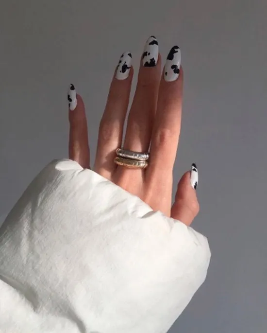 Белый маникюр с черными пятнами на длинных овальных ногтях