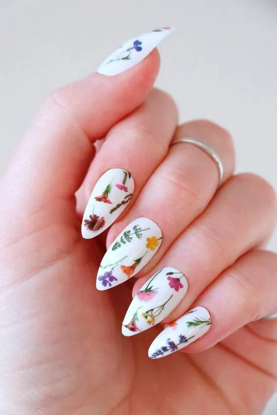 Белый маникюр с мелкими разноцветными цветами на длинных острых ногтях