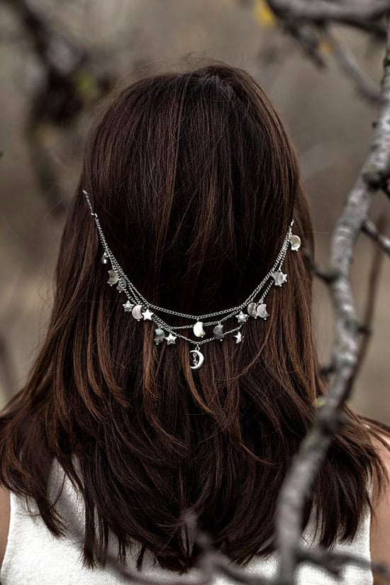 Девушка с распущенными темными волосами с серебренными цепочками с подвесками
