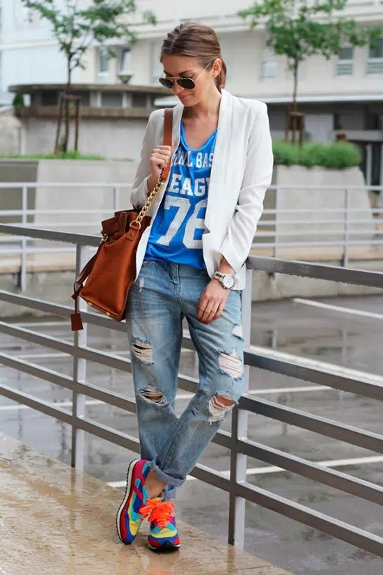 Девушка в рванных джинсах, голубая футболка, белый пиджак и разноцветные кроссовки