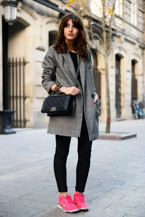 Девушка в сером простом пальто, черные облегающие джинсы и розовые кроссовки