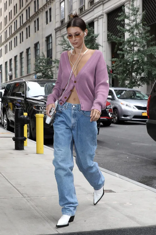 Девушка в широких прямых джинсах, фиолетовый кардиган и белые сапоги