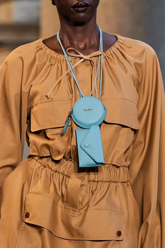 Модель в бежевом платье на резинке с карманами, образ дополняет голубая сумочка мини на шее от max mara