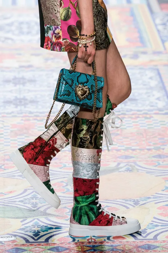 Модель в необычных разноцветных сапогах на шнуровке, голубая мини сумочка из змеинной кожи с золотыми цепочками от Dolce & Gabbana
