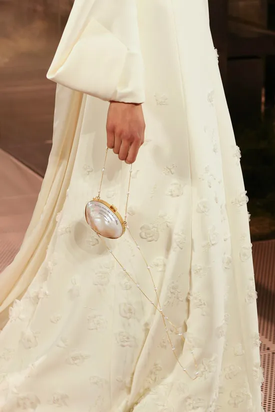 Модель в широком белом платье в пол и с маленькой овальной сумочкой с тонкой золотой цепочкой от fendi