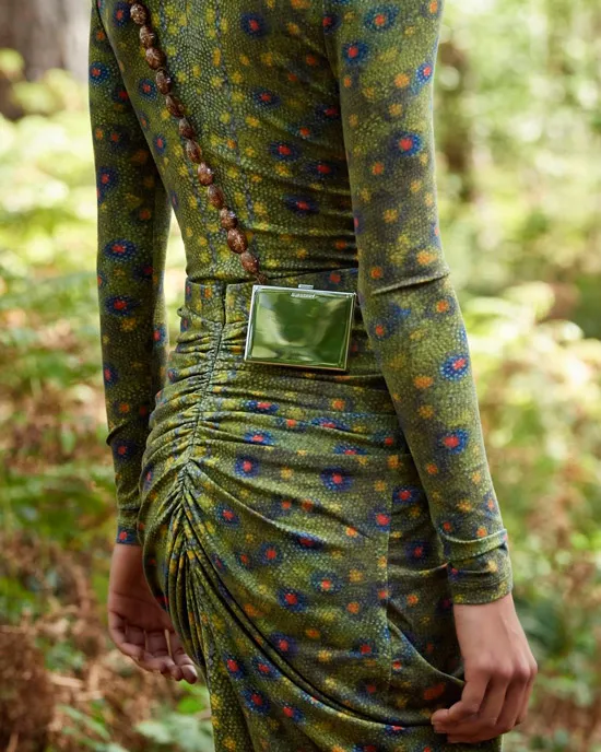 Модель в зеленом обтягивающем платье с длинными рукавами и глянцевой мини сумкой на поясе от burberry