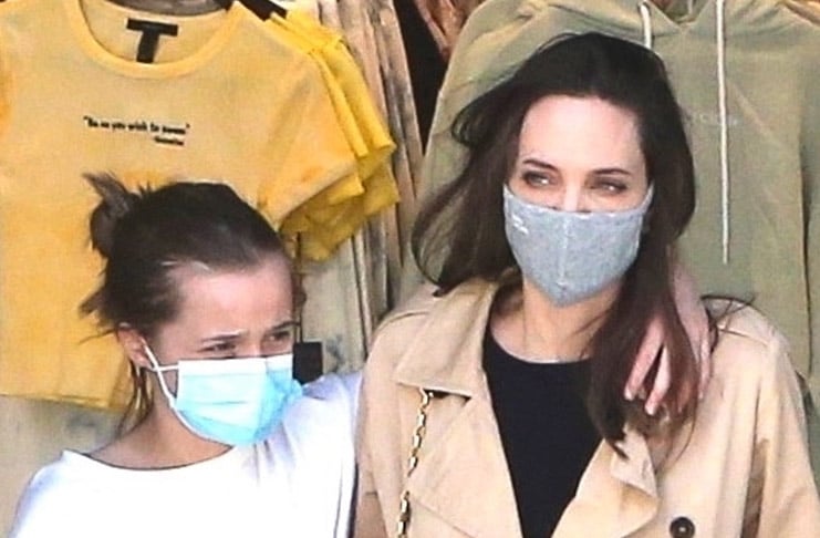 Анджелина Джоли в плаще и джинсах, счастливая выходит из магазина обнимая дочь