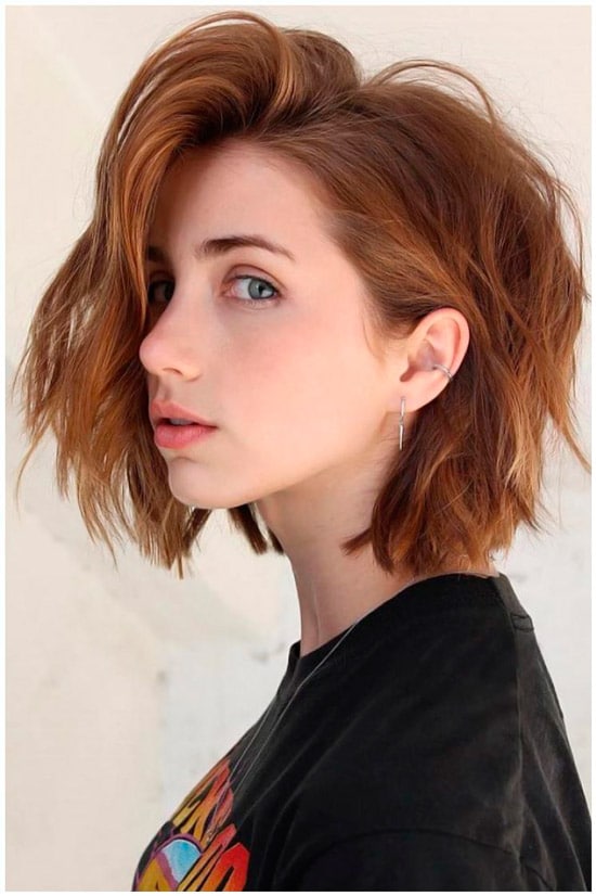 Девушка с пышной многослойной стрижкой на рыжих волосах средней длины
