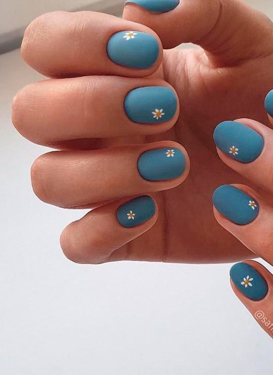 Синий матовый маникюр с маленькими белыми ромашками на коротких овальных ногтях
