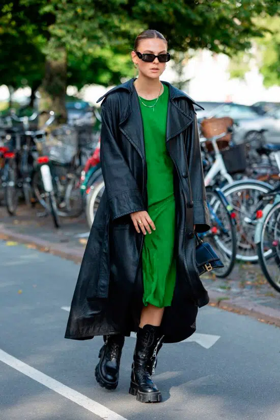 Девушка в зеленом платье миди, черном кожаном плаще и ботинках