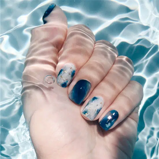 Синий морской маникюр с золотой фольгой на ногтях средней длины