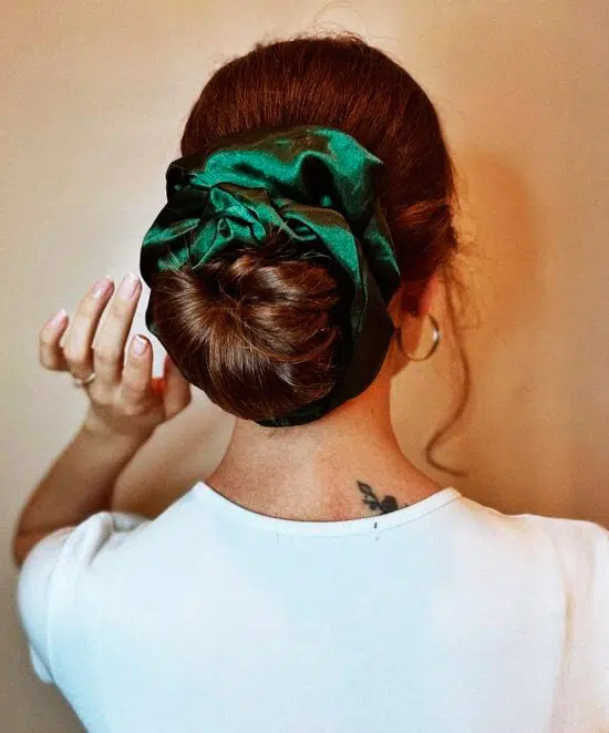 Девушка с ухоженным пучком и зеленой резинкой на натуральных волосах
