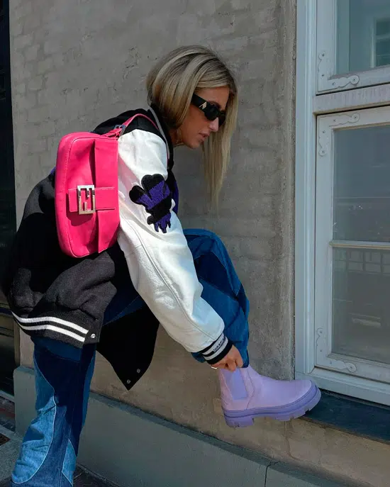 Девушка в свободных джинсах, спортивной куртке и интересных фиолетовых ботинках