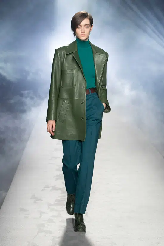 Девушка в зеленной удлиненной куртке, прямых брюках с ремнем и водолазке