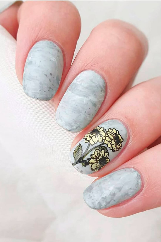 Текстурный серый маникюр с цветочным акцентом на овальных ногтях средней длины