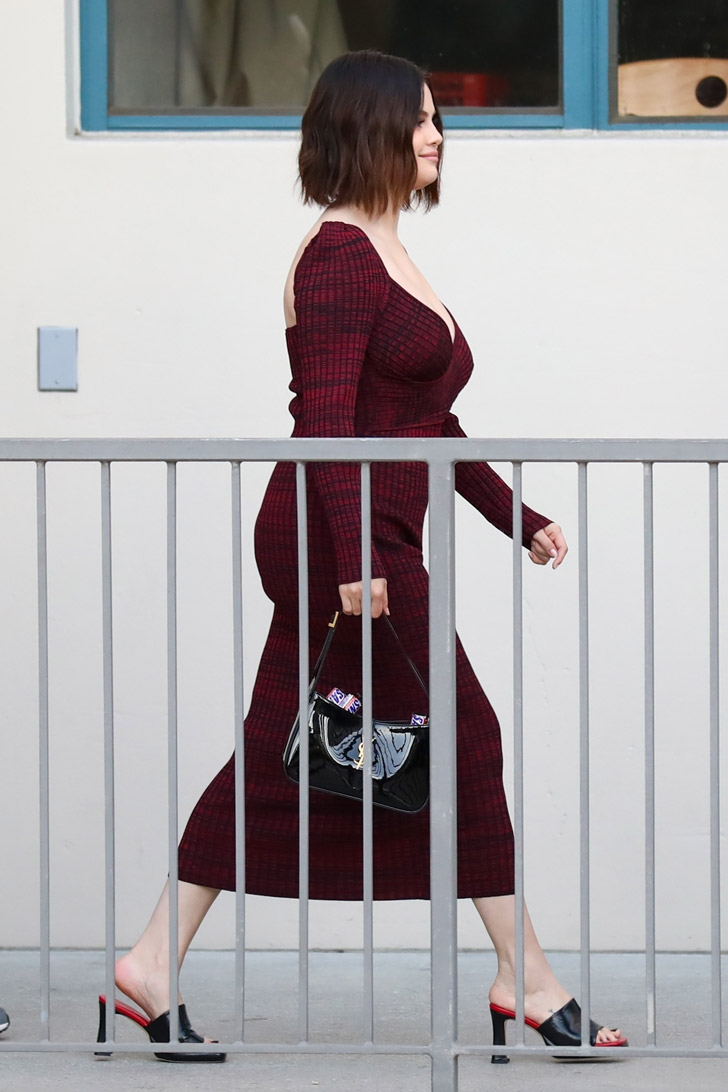 Селена Гомес в бордовом платье и сумкой со сникерсами