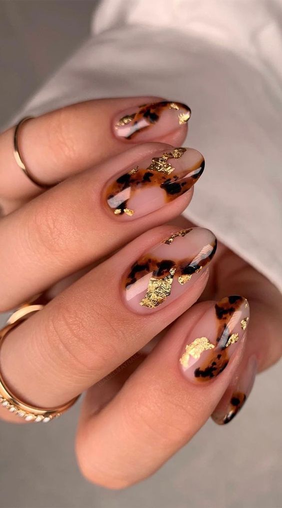 Маникюр с золотыми хлопьями и черепаховым принтом на овальных ногтях