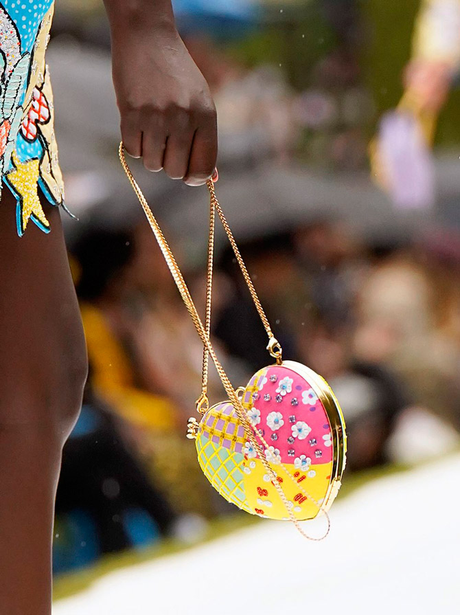 Модель с разноцветной сумочкой в виде сердца с золотой цепочкой