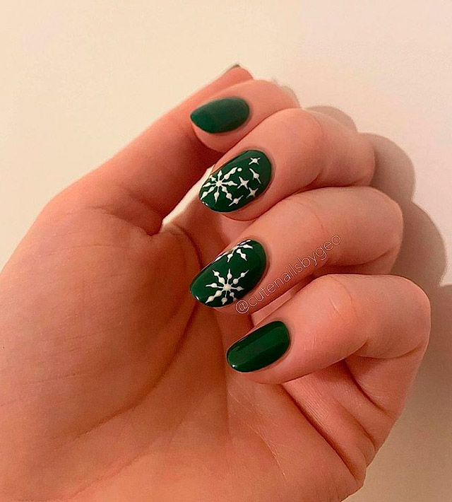 Зеленый маникюр с белыми снежинками на овальных натуральных ногтях