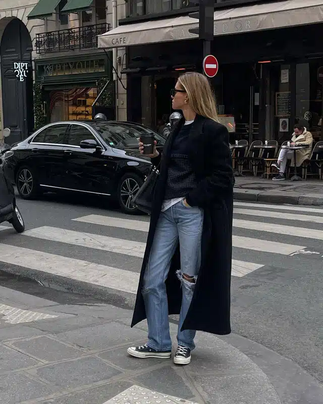 Девушка в прямых рваных джинсах, черном свитере и длинном пальто