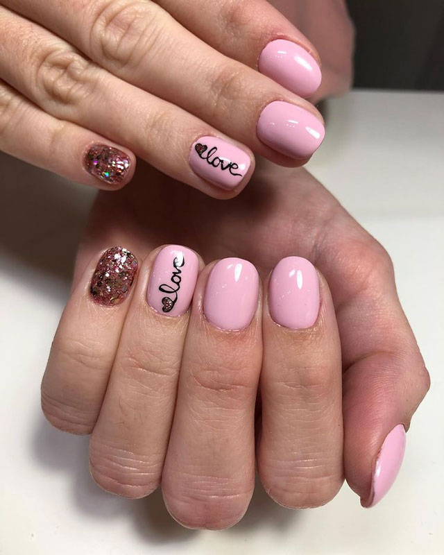 Нежно розовый маникюр с надписью и блестками на коротких ухоженных ногтях