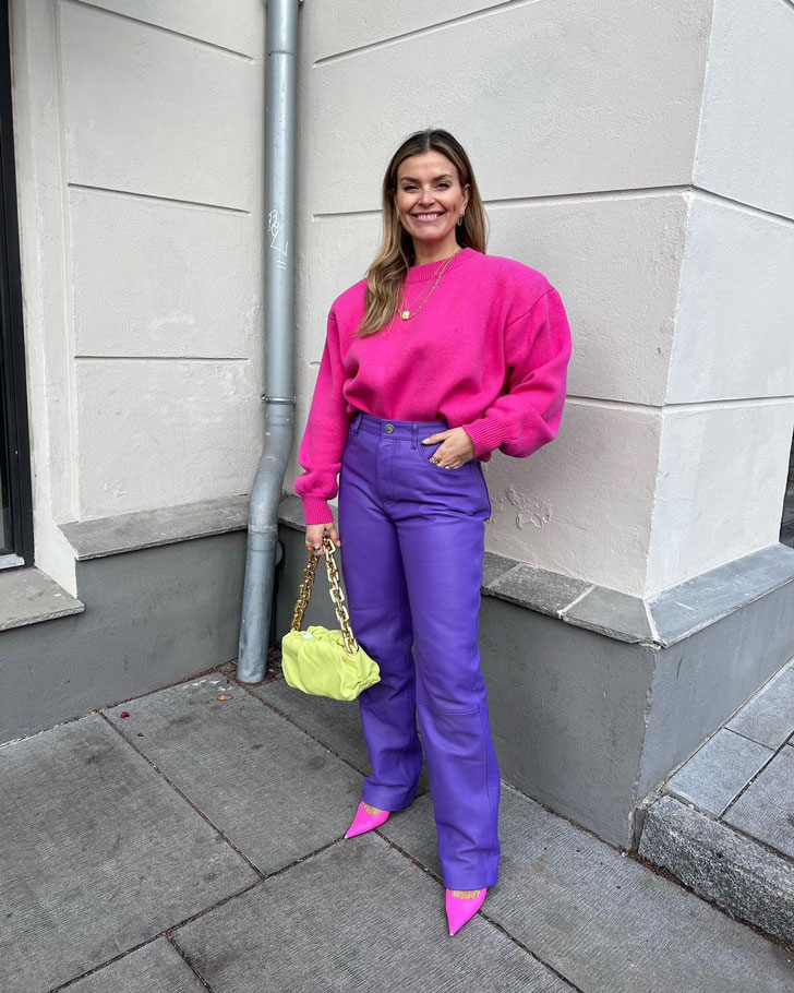 Девушка в фиолетовых кожаных брюках, розовом свитере и розовых туфлях лодочках