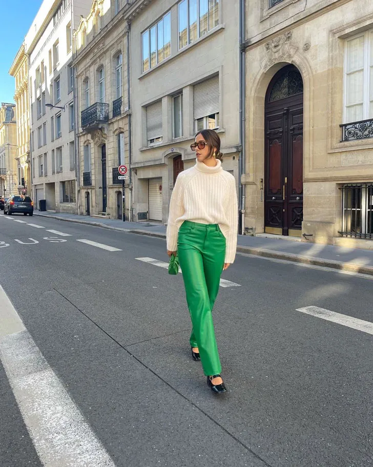 Девушка в зеленых кожаных брюках, бежевом свитере и лакированных туфлях