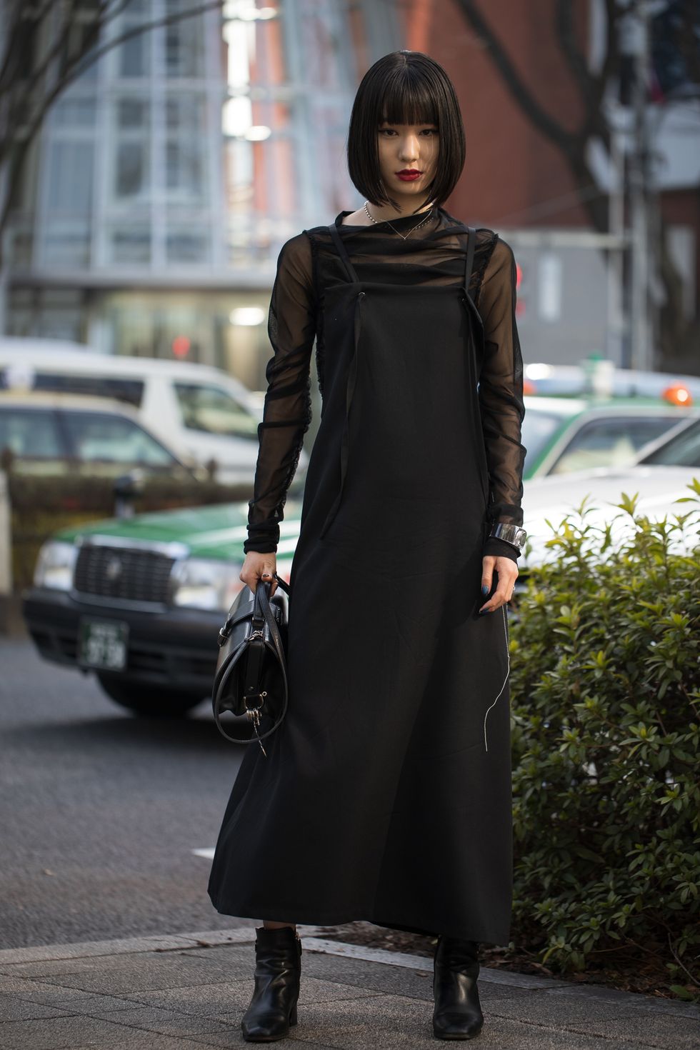 Девушка в длинном черном платье и в ботильонах на невысоком каблуке