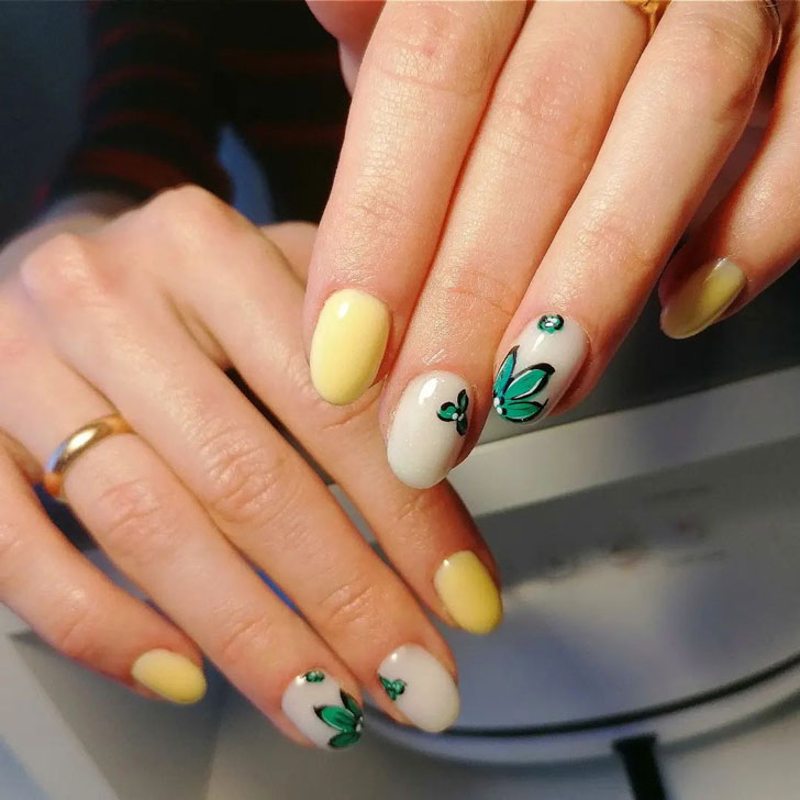 Желтый маникюр с зеленым принтом на овальных ногтях