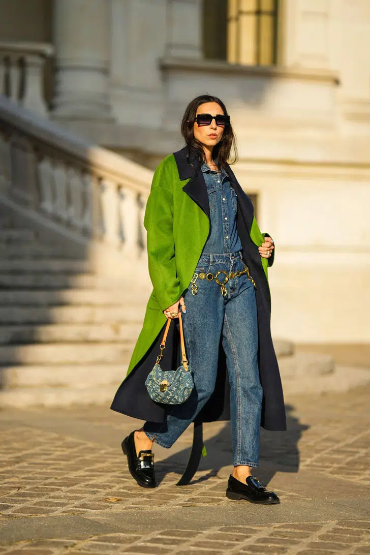 Девушка в прямых джинсах, джинсовой рубашке и ярком зеленом пальто