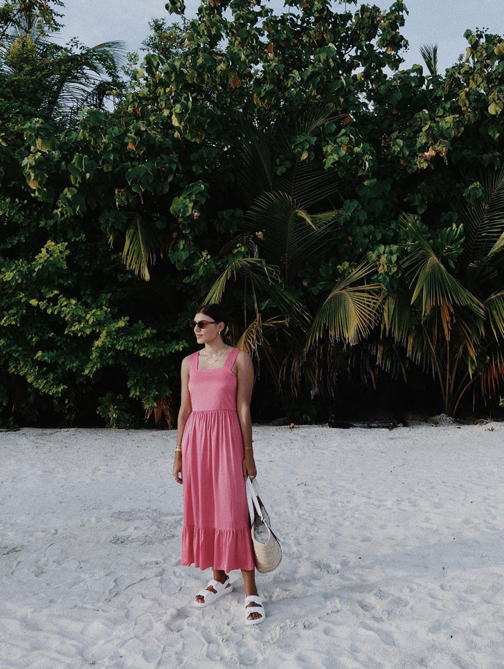 Девушка в розовом длинном сарафане и белых сандалиях