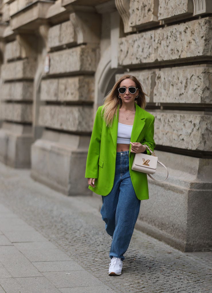 Девушка в широких джинсах, зеленом пиджаке оверсайз и белых кроссовках