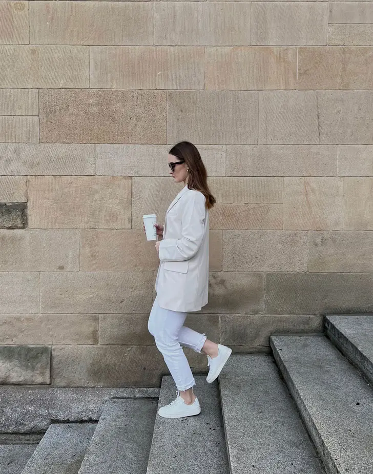 Девушка в укороченных белых джинсах, пиджаке оверсайз и белых кедах