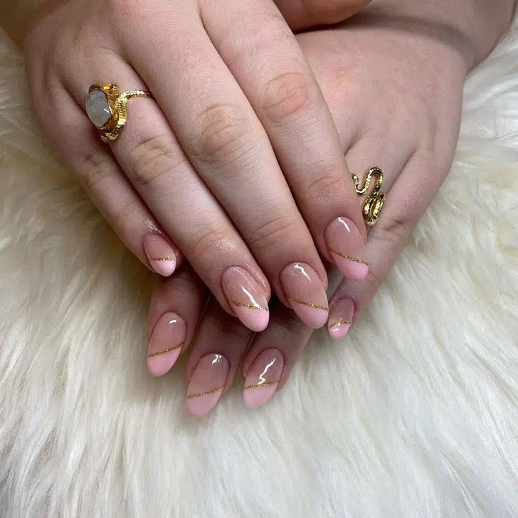 Диагональный розовый френч с золотыми блестками на овальных ногтях