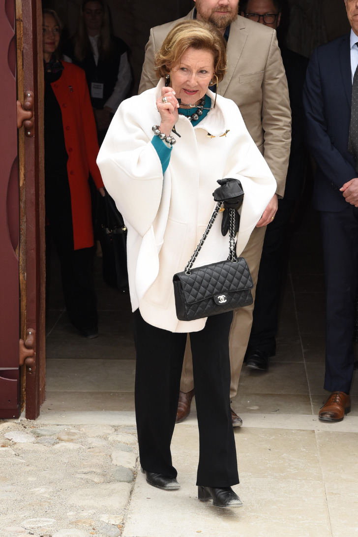 Королева Соня в брюках, белом пальто и пышной прической