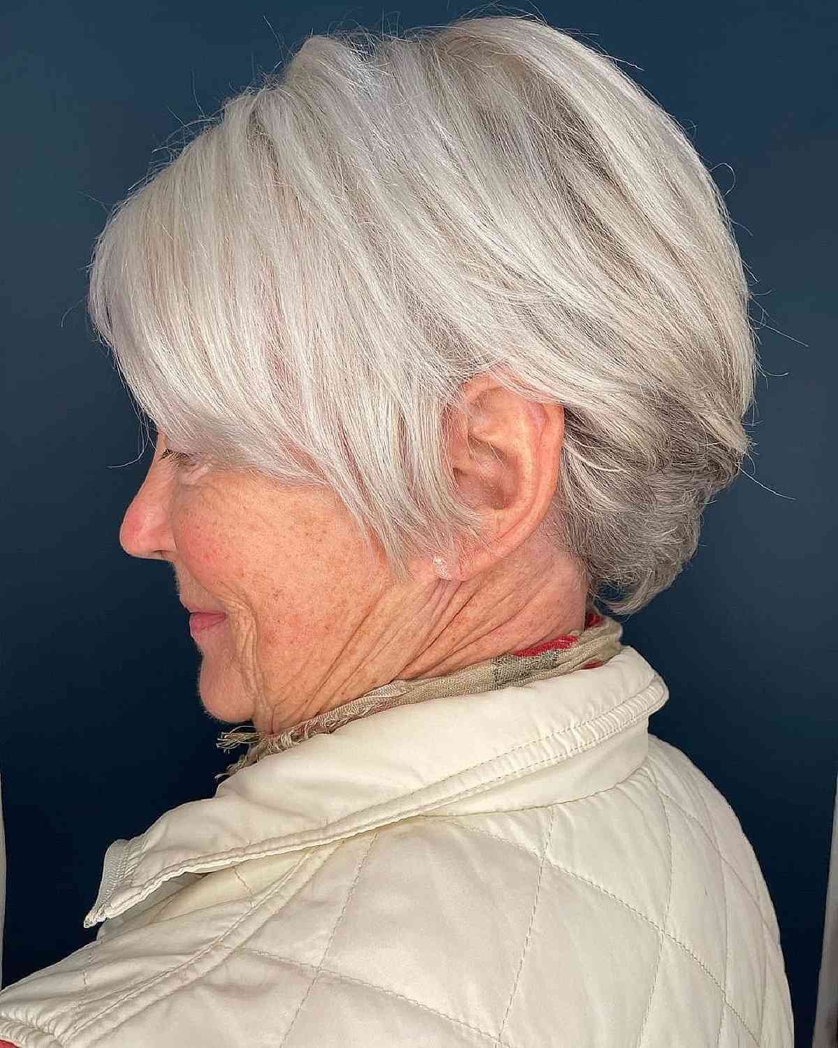 Женщина с короткой многослойной стрижкой с боковой челкой на седых волосах
