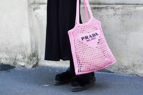 Девушка с розовой вязанной сумкой с логотипом