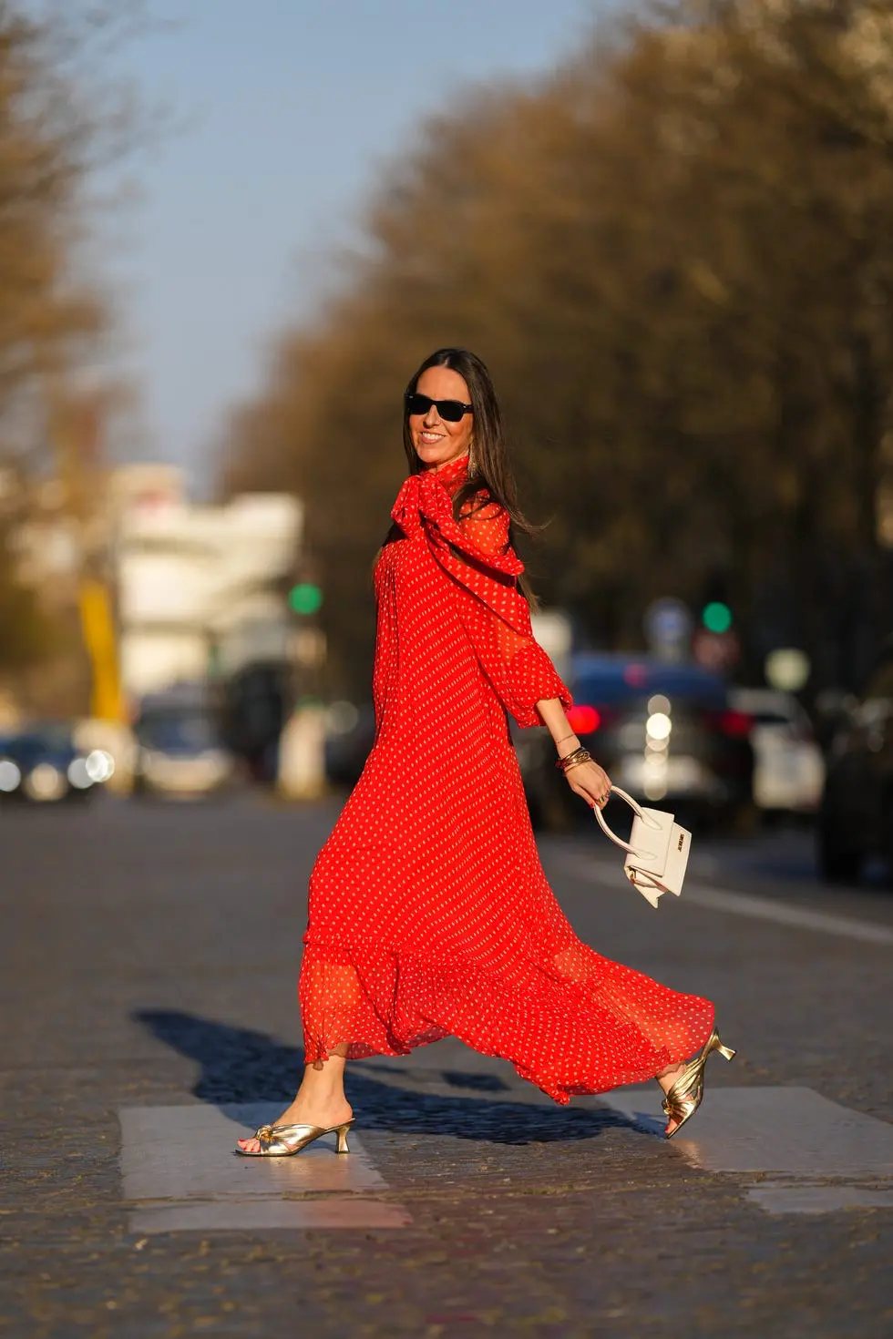 Девушка в красном легком платье макси и золотых мюли на низком каблуке