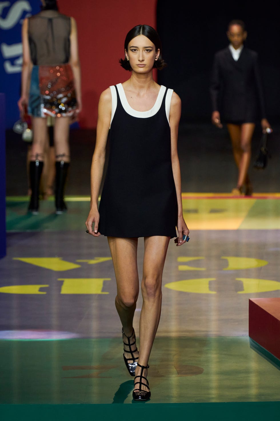 Модель в черном мини платье и белой майке от Christian Dior