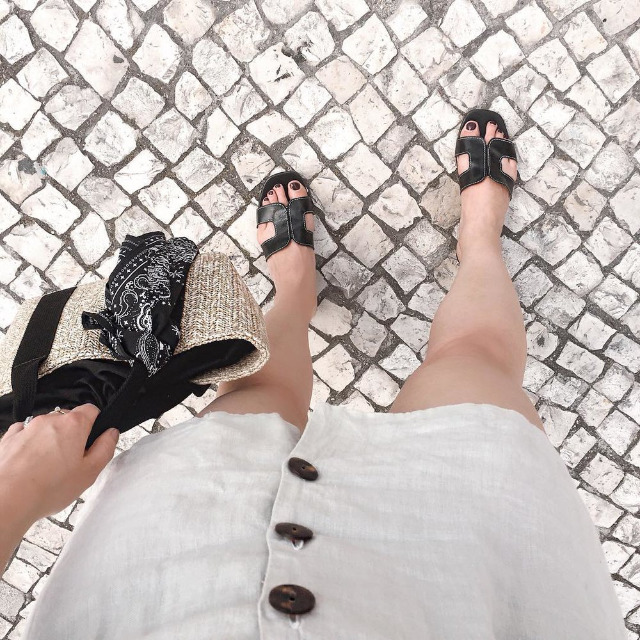 Девушка в короткой летней юбке и популярных летних сандалиях