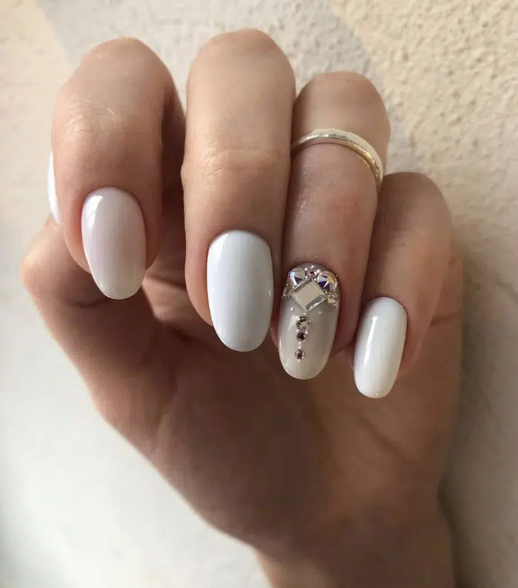 Шикарный белый маникюр с кристаллами на овальных ногтях средней длины